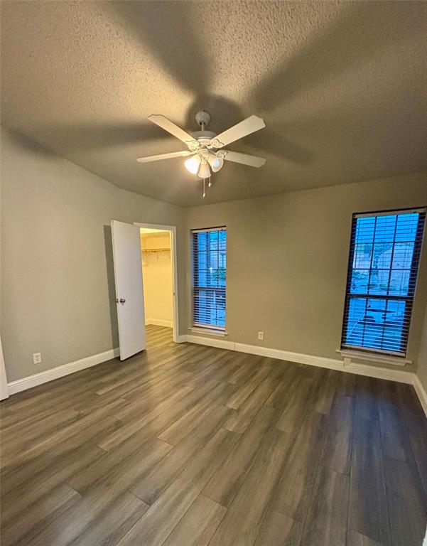 11655 Audelia Road, Unit 1304 Dallas, TX 75243 - Photo 11 of 11 Unfurnished bedroom with a textured ceiling, a walk in closet, dark wood-style flooring, and a ceiling fan