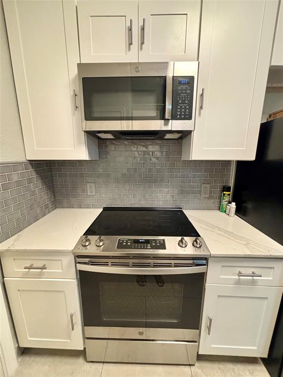 11655 Audelia Road, Unit 1304 Dallas, TX 75243 - Photo 3 of 11 Kitchen with stainless steel appliances, light stone counters, white cabinetry, and tasteful backsplash