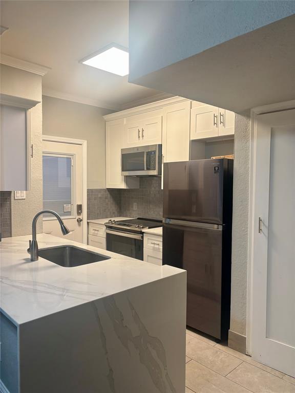 11655 Audelia Road, Unit 1304 Dallas, TX 75243 - Photo 4 of 11 Kitchen with light stone countertops, white cabinetry, stainless steel appliances, backsplash, and crown molding