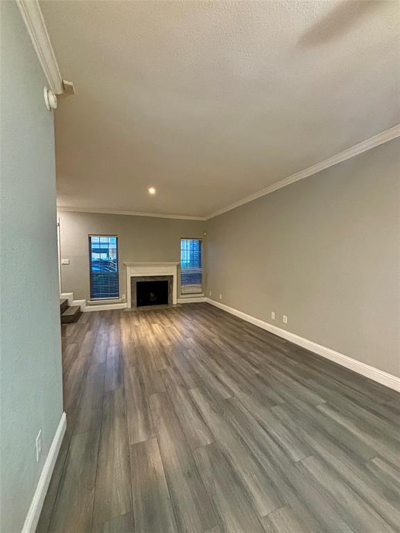 11655 Audelia Road, Unit 1304 Dallas, TX 75243 - Photo 5 of 11 Unfurnished living room featuring ornamental molding, dark wood finished floors, and a fireplace