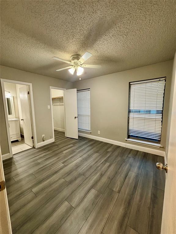 11655 Audelia Road, Unit 1304 Dallas, TX 75243 - Photo 8 of 11 Unfurnished bedroom with a walk in closet, dark wood finished floors, a textured ceiling, ceiling fan, and ensuite bath