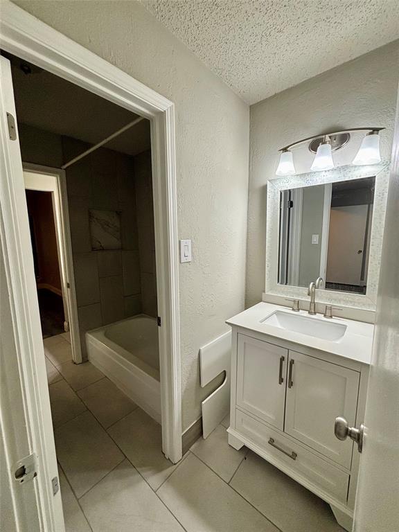 11655 Audelia Road, Unit 1304 Dallas, TX 75243 - Photo 9 of 11 Full bath featuring a textured wall, vanity, a textured ceiling, light tile patterned floors, and shower / bath combination