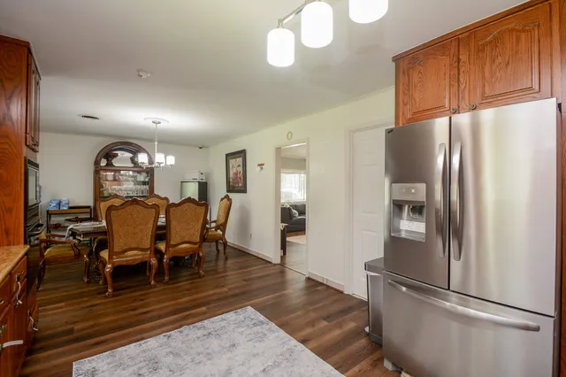 a kitchen with stainless steel appliances granite countertop a refrigerator a stove a dining table and chairs with wooden floor