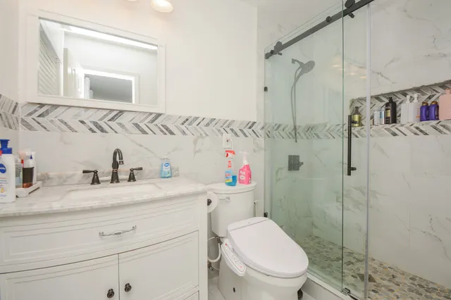 a bathroom with a toilet sink vanity granite and shower