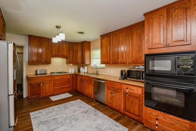 a kitchen with stainless steel appliances granite countertop wooden cabinets a stove top oven a sink and dishwasher