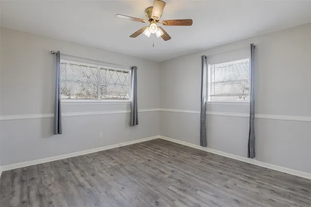 a view of empty room with wooden floor and fan