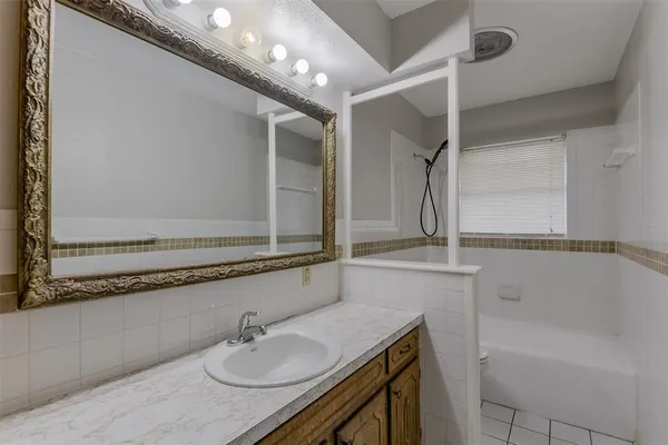 a bathroom with a granite countertop sink a mirror and a bathtub