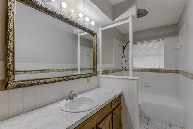 a bathroom with a granite countertop sink a mirror and a bathtub
