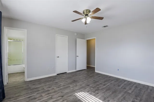 an empty room with wooden floor and ceiling fan