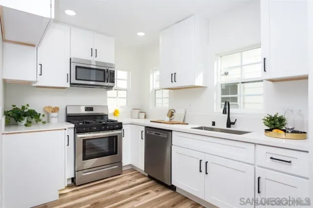 a kitchen with stainless steel appliances white cabinets a sink stove and a window