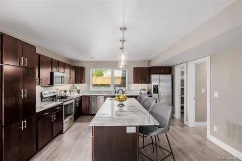 a large kitchen with kitchen island a stove a refrigerator a sink dishwasher a dining table and chairs with wooden floor