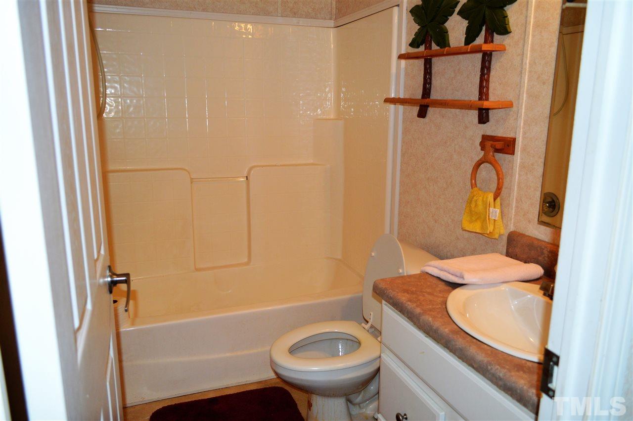 8701 Walter Myatt Road Willow Spring, NC 27592 - Photo 11 of 13 a bathroom with a granite countertop sink toilet and shower