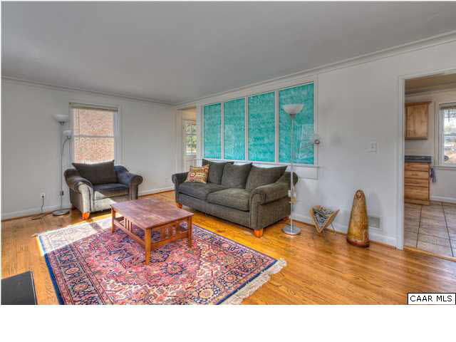 1407 Rutledge Avenue Charlottesville, VA 22903 - Photo 4 of 24 A small foyer opens to the bright living room. Hardwood floors in honey tones warm the main level. A framed opening/pass through to the kitchen adds architectural interest.