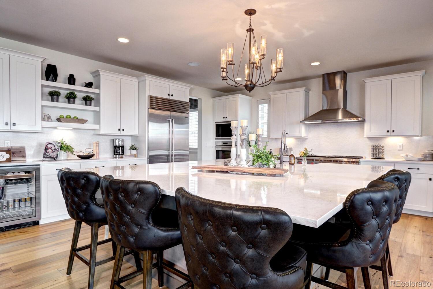 a kitchen with stainless steel appliances granite countertop a table chairs stove and white cabinets