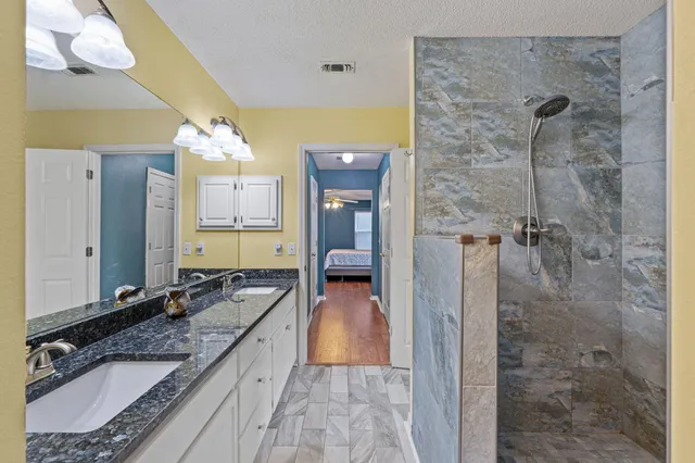 a bathroom with a granite countertop shower a toilet and a sink