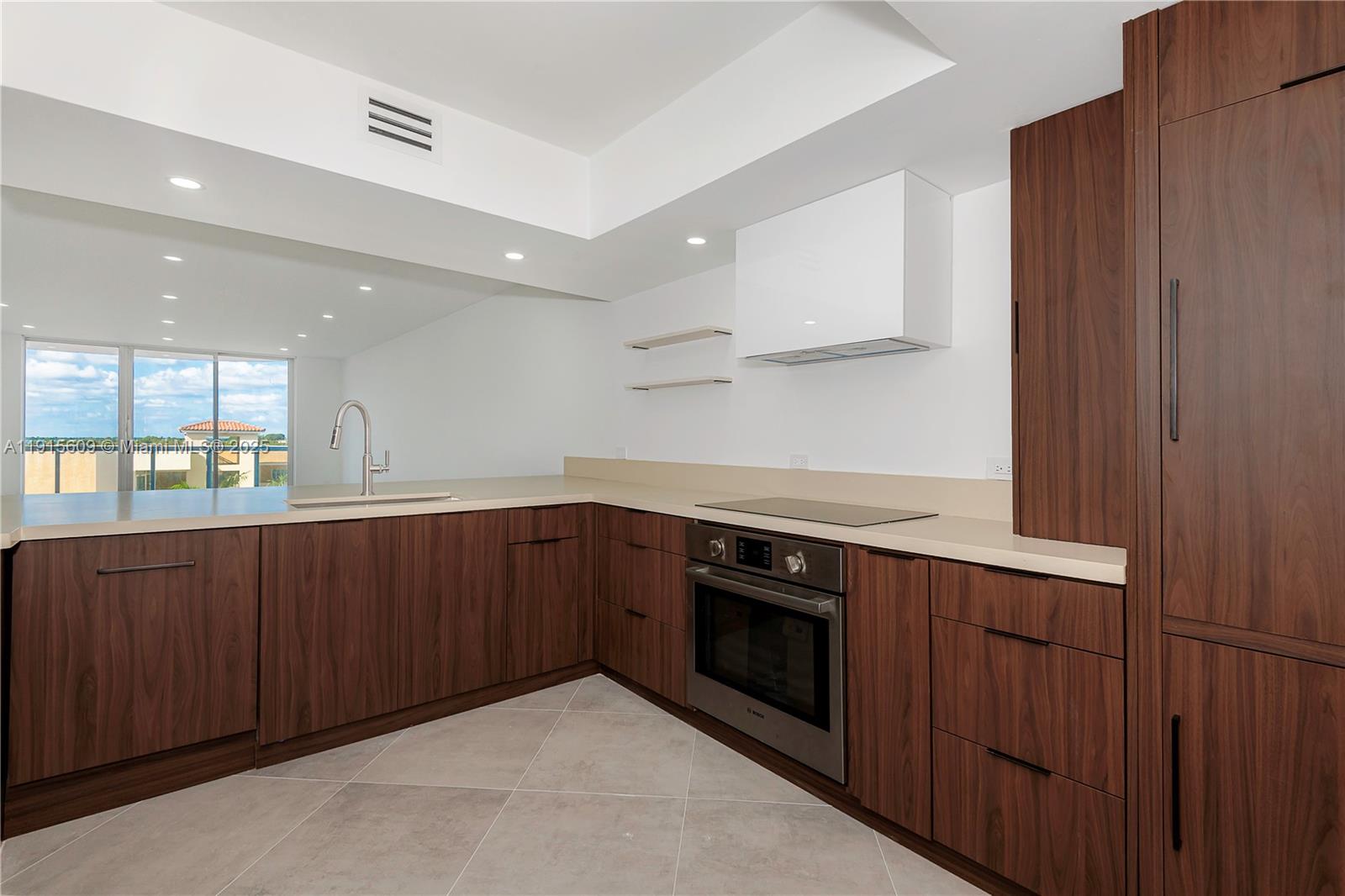 8855 Collins Avenue, Unit 6E Surfside, FL 33154 - Photo 9 of 24 a kitchen with wooden cabinets and a sink