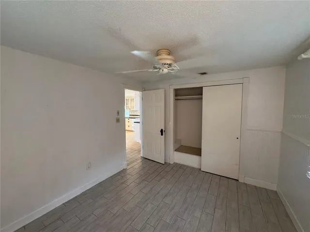 a view of a room with wooden floor and a ceiling fan