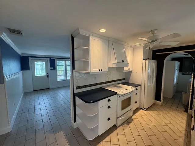 a kitchen with granite countertop a stove a sink and a refrigerator
