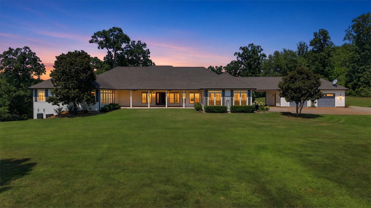 181 Sentell Road Williamston, SC 29697 - Photo 45 of 46 An expansive green lawn unfolds behind this classic single-story country home under a twilight sky.