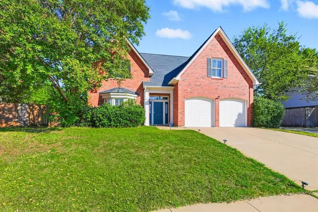 a view of a brick house with a big yard and large trees