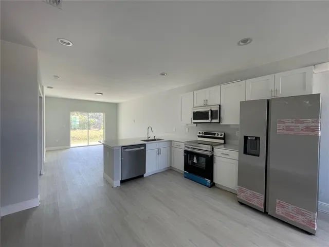 a kitchen with a refrigerator stove and wooden floor