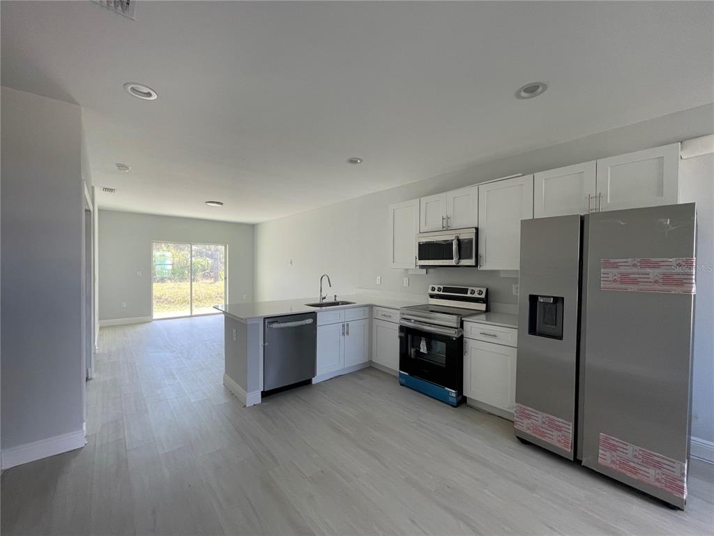 10249 Burlington Avenue Englewood, FL 34224 - Photo 3 of 12 a kitchen with a refrigerator stove and wooden floor