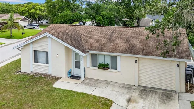 a view of a white house with a small yard and large tree