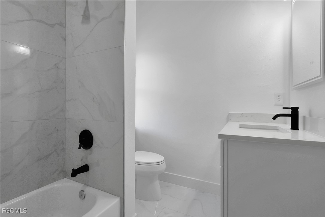 2810 44th Street Southwest Lehigh Acres, FL 33976 - Photo 28 of 31 a bathroom with a toilet a sink a mirror and vanity