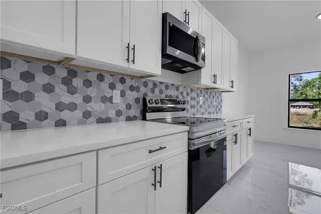 a kitchen with stainless steel appliances granite countertop white cabinets a stove a sink and dishwasher