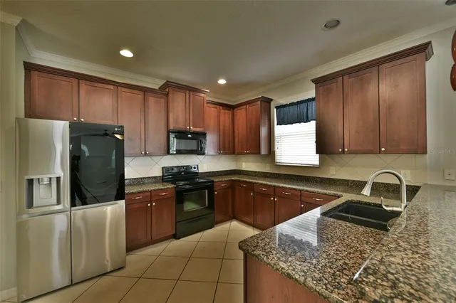 a kitchen with stainless steel appliances granite countertop a sink stove refrigerator and cabinets