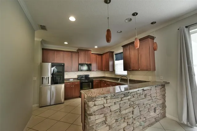 a kitchen with stainless steel appliances granite countertop a sink refrigerator and cabinets