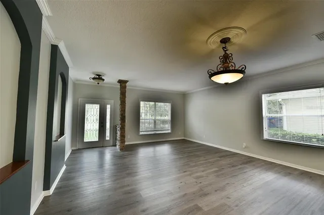 a view of an empty room with a window and wooden floor
