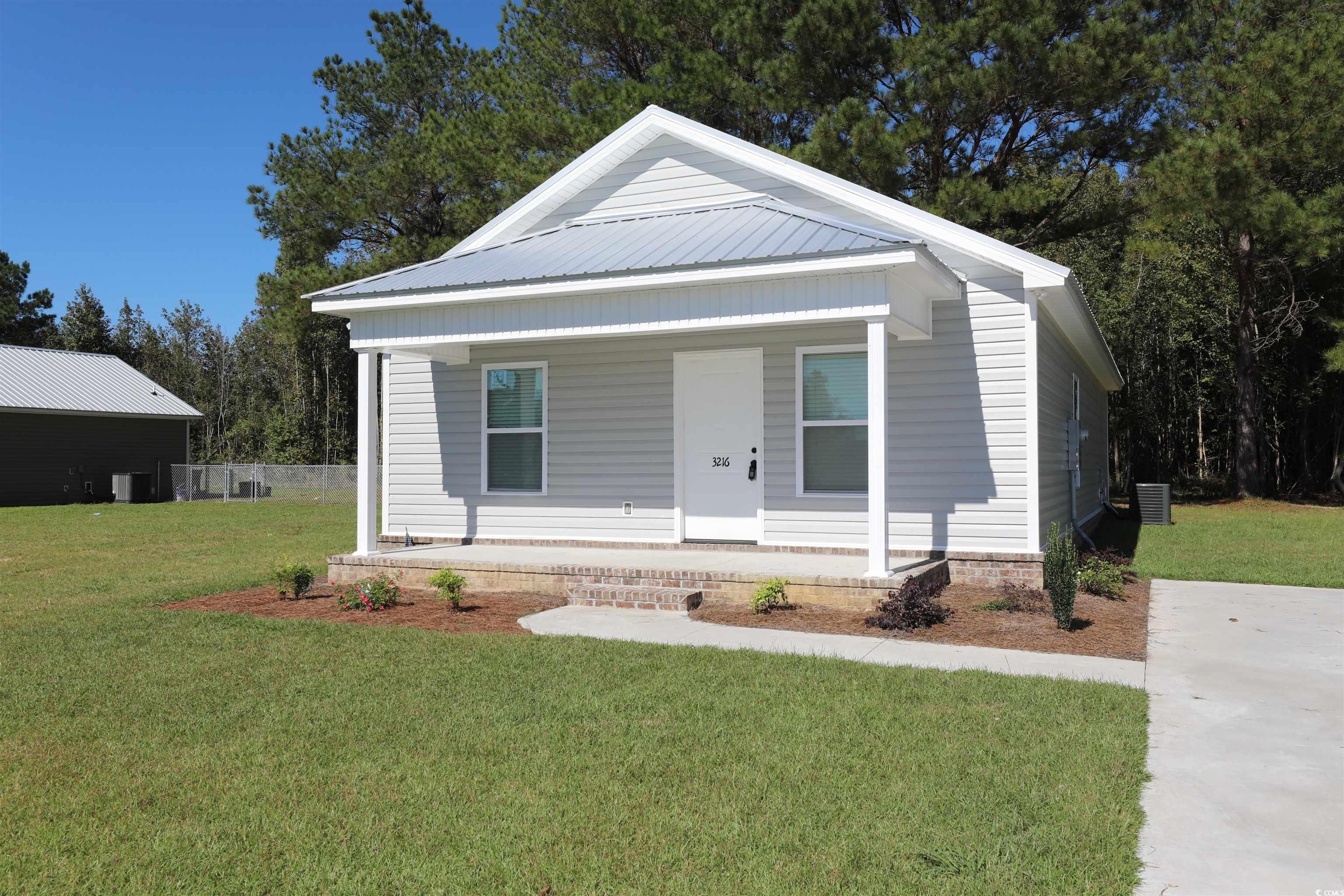 View of front of house with covered porch and a front lawn