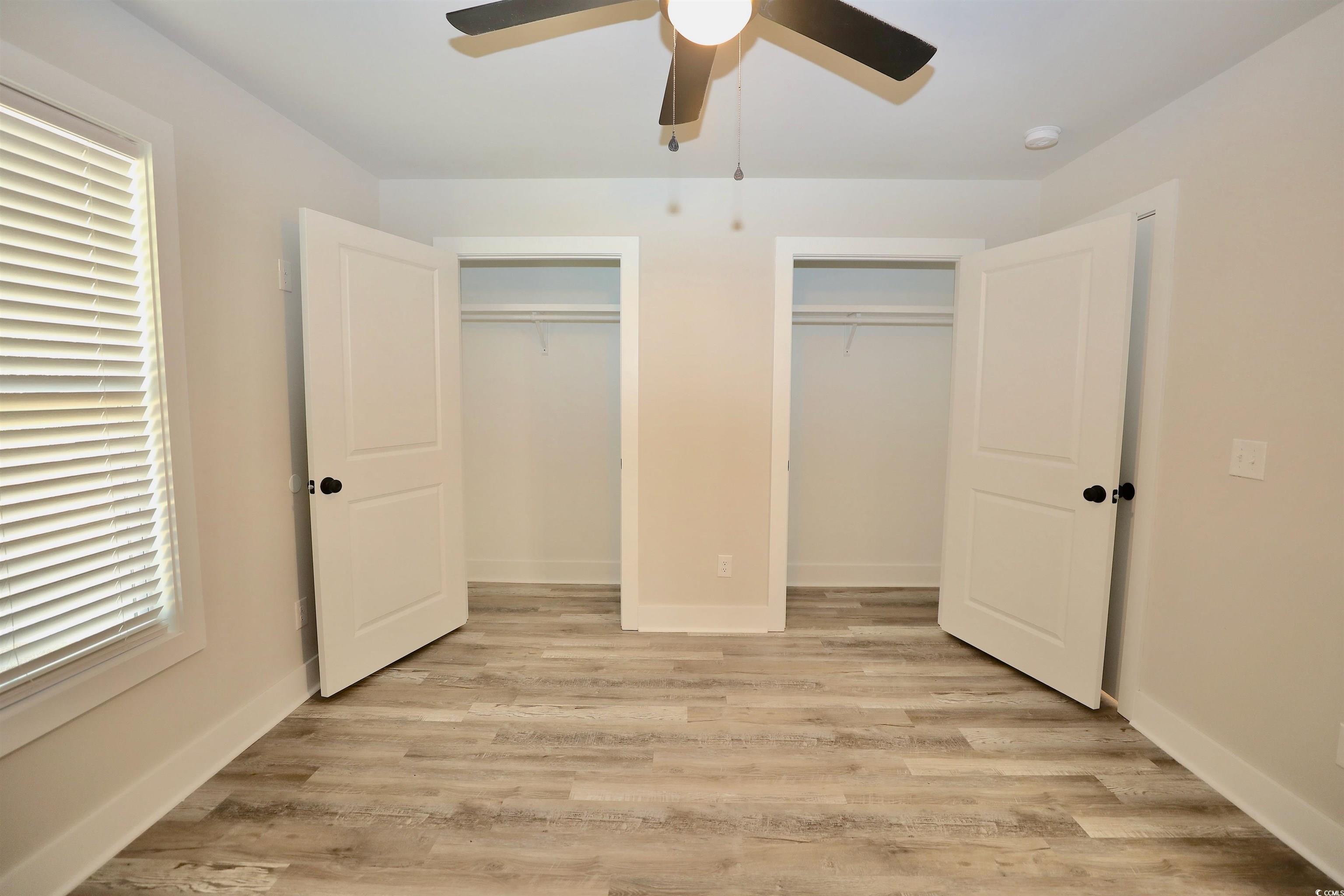 3216 South Hill Road Timmonsville, SC 29161 - Photo 9 of 19 Unfurnished bedroom with multiple closets, light wood-style floors, and a ceiling fan