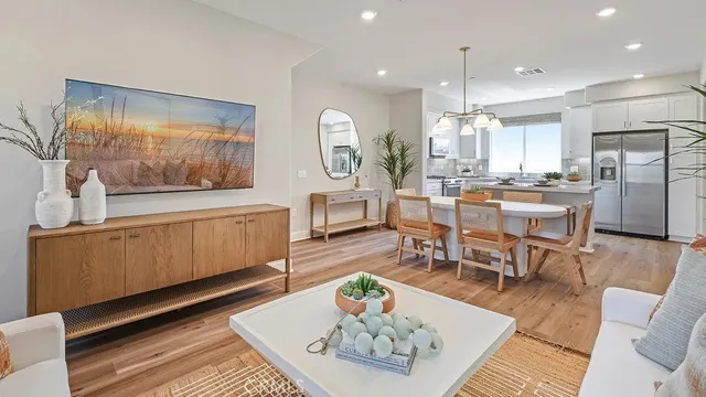 a living room with stainless steel appliances furniture a rug kitchen view and a chandelier