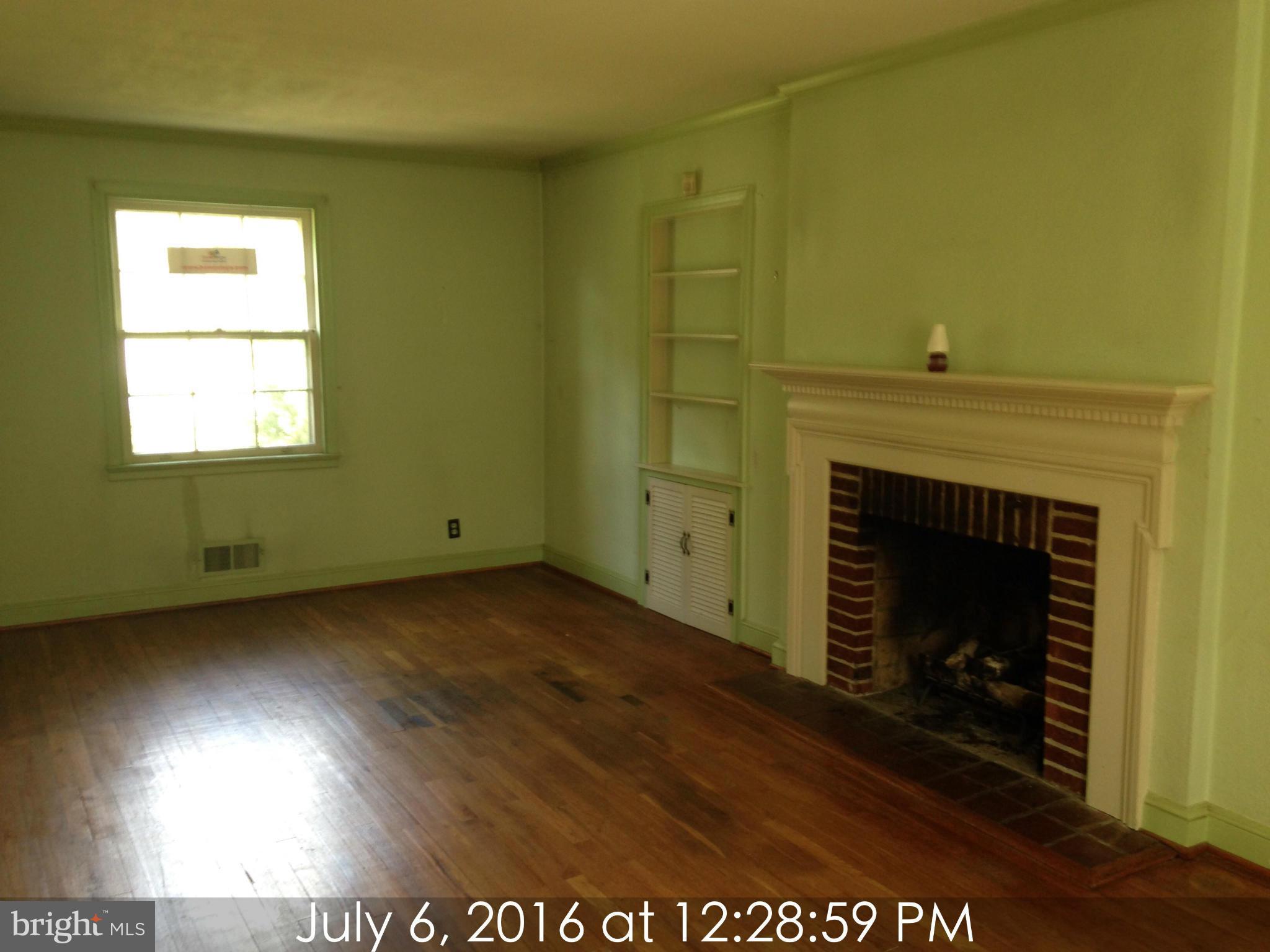 3715 Buckingham Road Baltimore, MD 21207 - Photo 2 of 9 a view of an empty room with a fireplace and a window