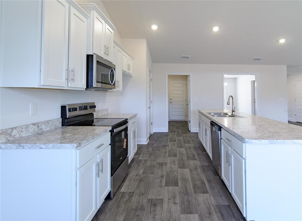 2 Seckel Court Palm Coast, FL 32164 - Photo 7 of 26 a kitchen with stainless steel appliances granite countertop wooden cabinets a sink a stove a microwave and wooden floors