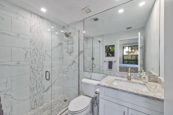 a bathroom with a granite countertop sink a toilet and shower