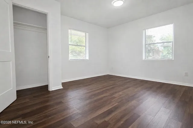 an empty room with wooden floor and windows