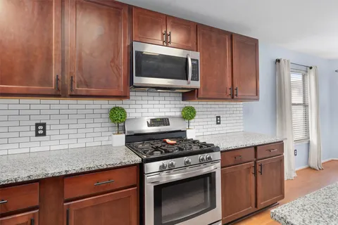 a kitchen with granite countertop stainless steel appliances a sink stove and cabinets
