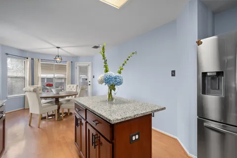 a kitchen with granite countertop kitchen island stainless steel appliances a dining table and chairs