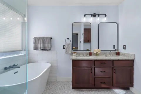 a bathroom with a granite countertop bathtub a double vanity sink and mirror