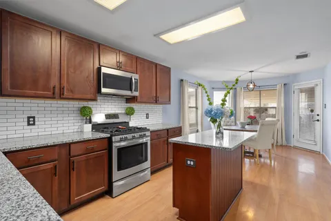 a kitchen with stainless steel appliances granite countertop wooden cabinets a sink dishwasher a stove and a refrigerator