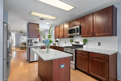 a kitchen with kitchen island granite countertop stainless steel appliances stove microwave refrigerator and sink