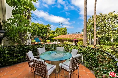 a view of a patio with couches table and chairs potted plants and palm trees