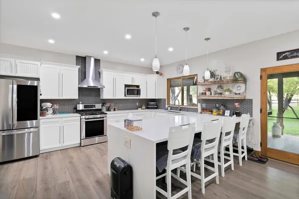 a kitchen with stainless steel appliances a microwave a stove a refrigerator a stove a sink a dining table and chairs
