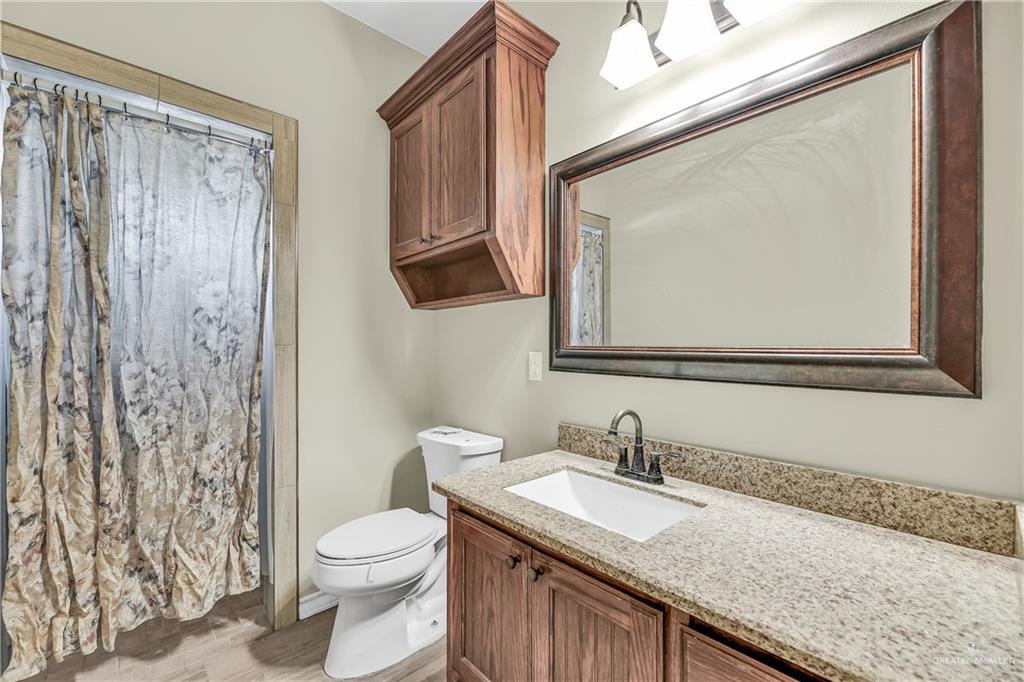 1106 Rio Blanco Street San Juan, TX 78589 - Photo 11 of 21 a bathroom with a granite countertop sink a toilet and a mirror