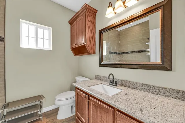 a bathroom with a granite countertop sink a toilet and a mirror