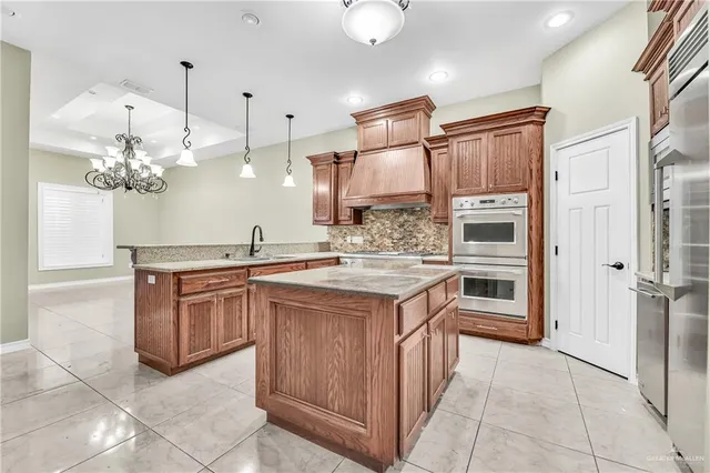 a kitchen with kitchen island granite countertop a sink cabinets and stainless steel appliances