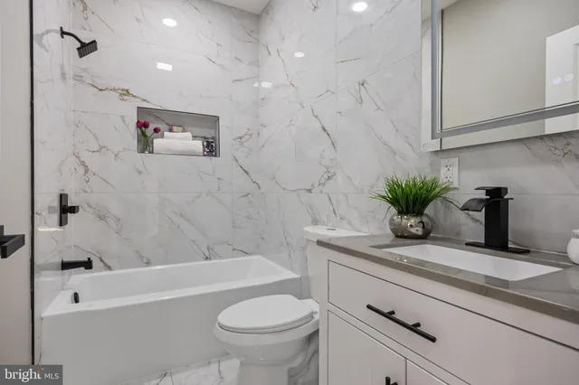 a bathroom with a granite countertop sink a toilet and bathtub